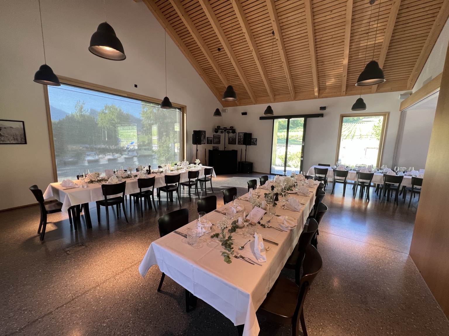 Festlich gedeckte Hochzeitstische mit dezentem DJ-Aufbau im Hintergrund